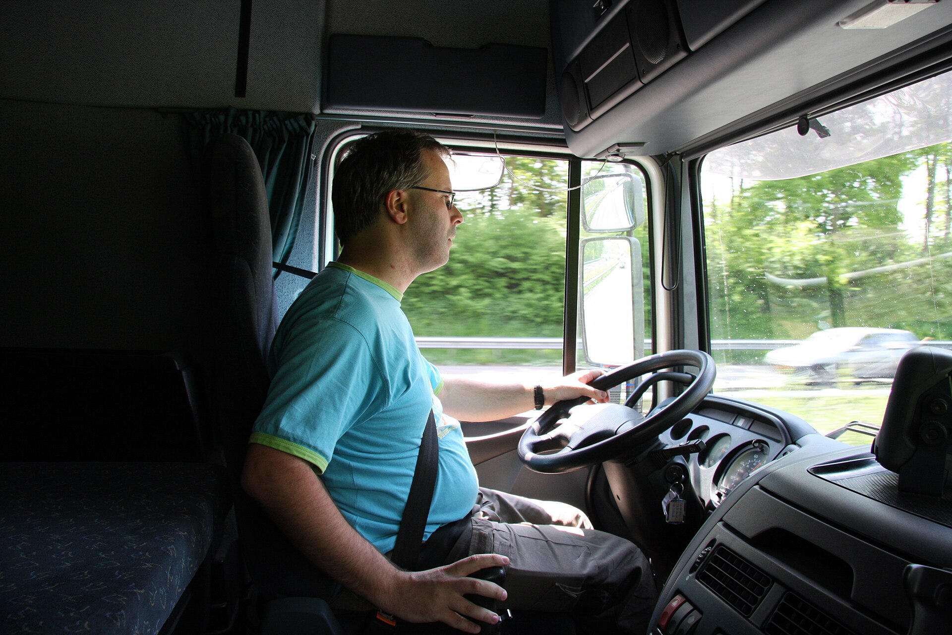 A contemporary truck driver in a modern lorry cab.